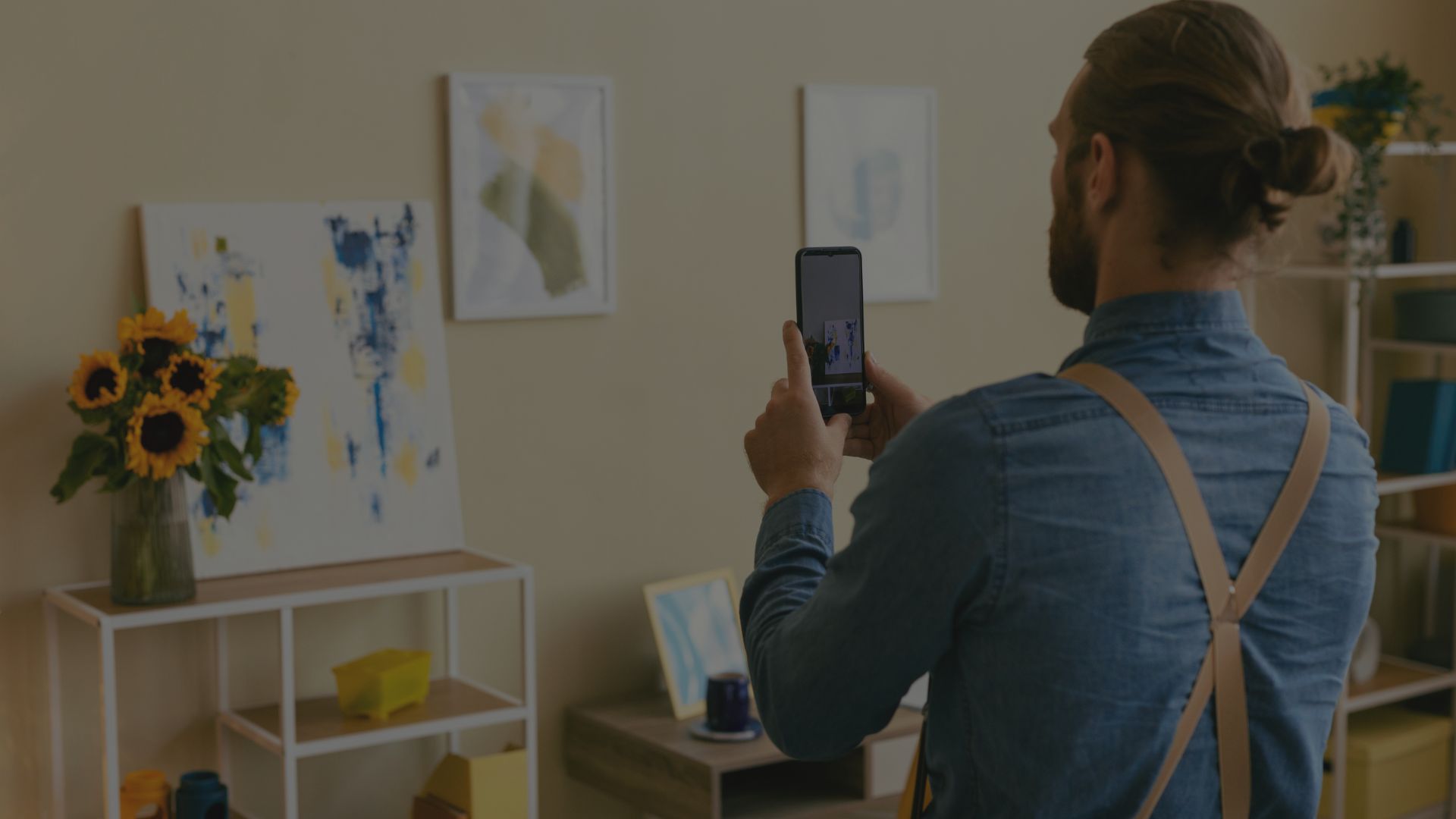 A man using a smartphone to take a photo of his artwork, representing documenting and sharing creative work on social media.